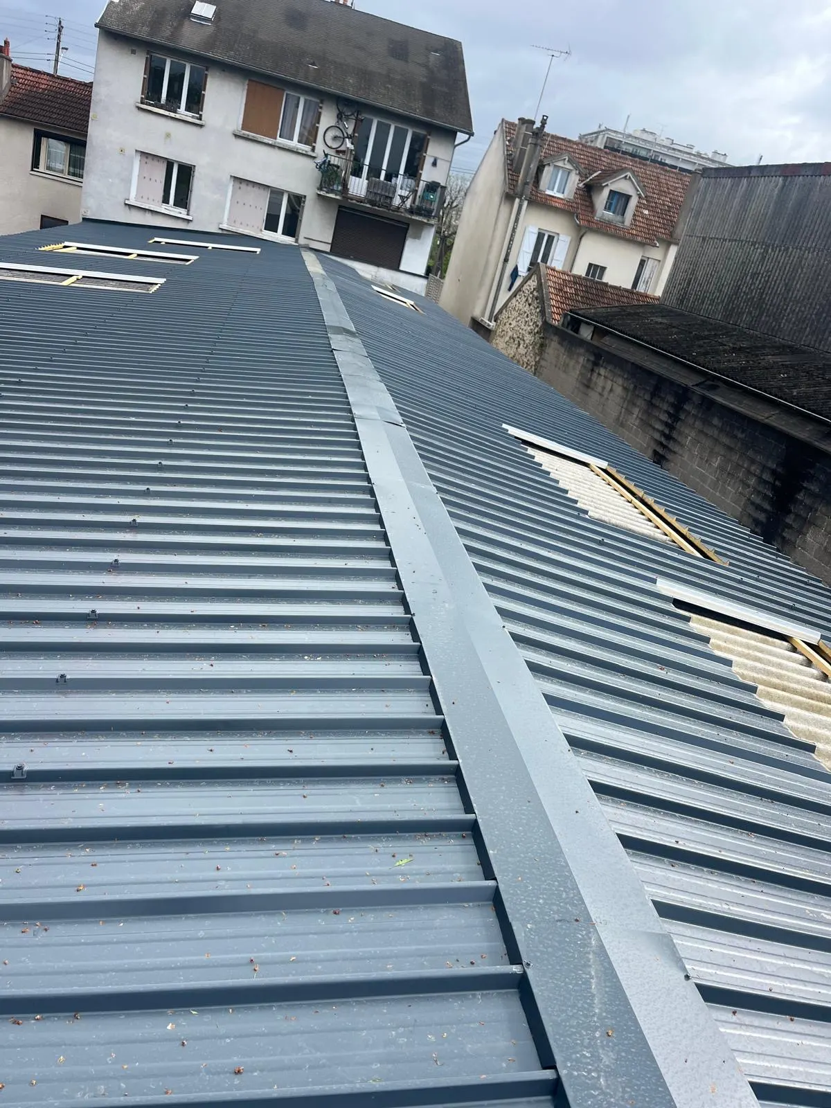 Couverture en bac acier — Lignes de couverture métallique sur un bâtiment urbain. Chantier en Île-de-France.